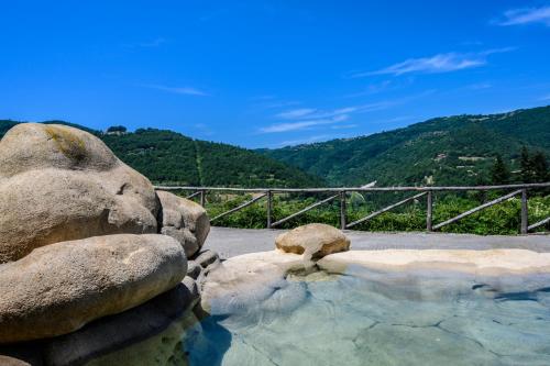 a pool of water with rocks and a mountain at Tenuta Pian D'Attesio - Agriturismo in Castelletto Soprano