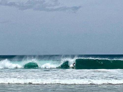 a surfer riding a large wave in the ocean at Villas Kalei in Playa Grande