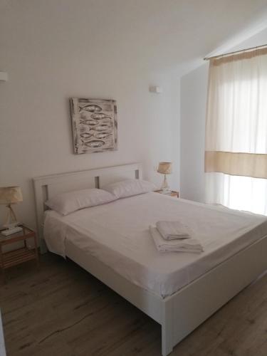 a white bedroom with a large bed and a window at Domo Green House in Villasimius