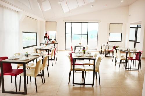 ein Esszimmer mit Tischen, Stühlen und Fenstern in der Unterkunft HOTEL OLIMPIA in Duitama