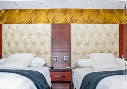 a bedroom with two beds and a large headboard at The Royal Courtyard in Matatiele