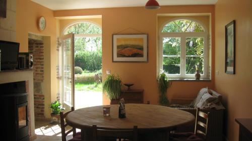 - un salon avec une table en bois et 2 fenêtres dans l'établissement Le Petit Bois, à Château-la-Vallière