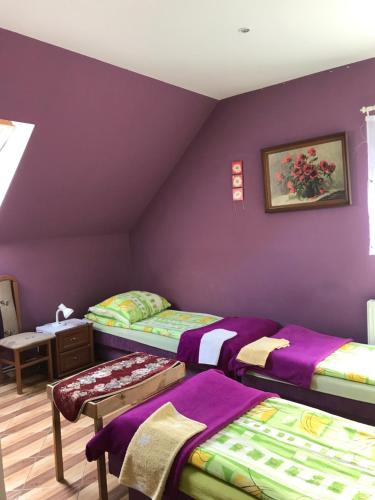 Zimmer mit 3 Betten und einer lila Wand in der Unterkunft Restauracja Łania in Koszalin