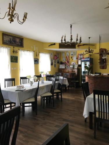 jadalnia z białymi stołami i krzesłami oraz żółtymi ścianami w obiekcie Restauracja Łania w Koszalinie