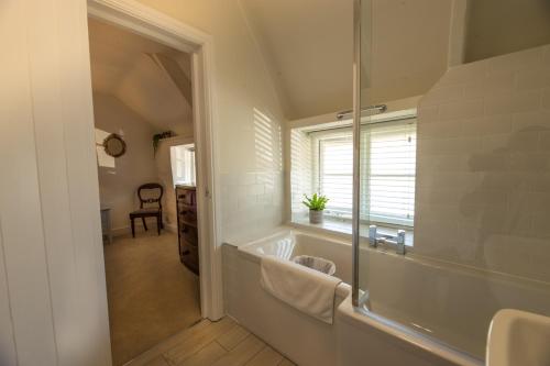 a bathroom with a tub and a sink and a mirror at The Cott Inn in Totnes