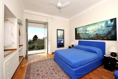 a bedroom with a blue bed and a large window at Residenza Villa Titina in SantʼAgata sui Due Golfi