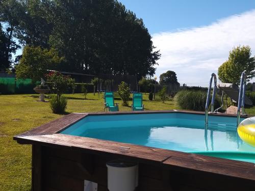 - une piscine dans une cour avec 2 chaises bleues dans l'établissement Gîte et Relais Equestre de Marie, à Tours-en-Vimeu