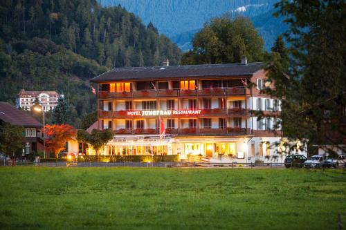 a hotel building with a sign on it in a field at Jungfrau Hotel in Wilderswil