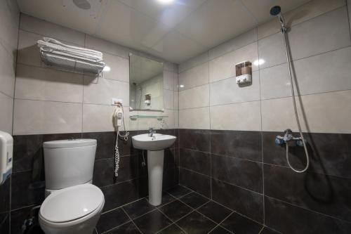 a bathroom with a toilet and a sink and a shower at England Vacation Hotel in Zhongli