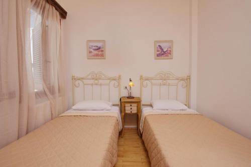 two twin beds in a room with a window at Theodora in Patitiri