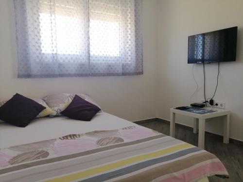 sypialnia z łóżkiem, telewizorem i oknem w obiekcie Apartments Venerea w Nin