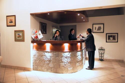 a man standing at a bar with two women behind it at Plaza Mayor Hotel in Puno