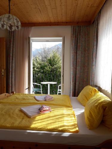 a bedroom with a bed with yellow sheets and a window at Gästehaus Lutschounig in Faak am See