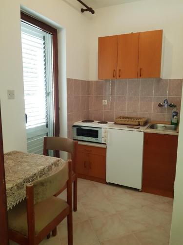 a kitchen with a stove and a sink and a table at Sobe i apartmani Marović in Petrovac na Moru