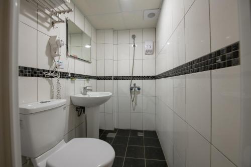 a white bathroom with a toilet and a sink at England Vacation Hotel in Zhongli