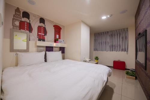 a bedroom with a large white bed in a room at England Vacation Hotel in Zhongli