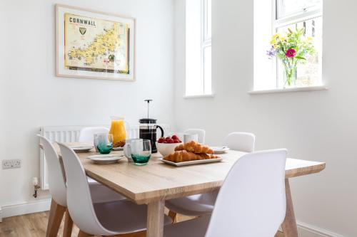 a dining room with a wooden table and white chairs at Ocean House in St Ives
