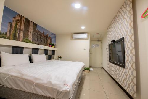a bedroom with a bed and a tv on a wall at England Vacation Hotel in Zhongli