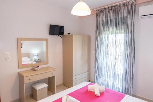a bedroom with a bed and a dresser and a mirror at Nikos Apartments in Ormos Panagias
