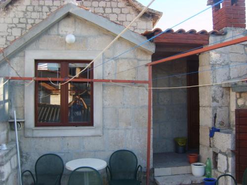 a house with a table and chairs in front of a window at Rooms Roso in Trogir