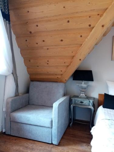 a chair in a bedroom with a wooden ceiling at U Hanki in Biały Dunajec