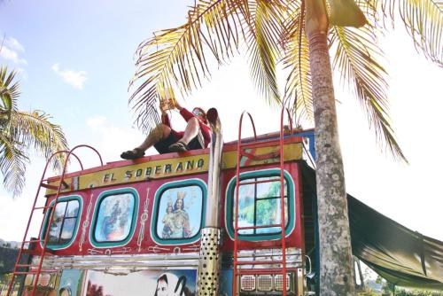a red double decker bus parked next to a palm tree at CASA KAYAM Art Hostel Coliving Coworking in Guatapé
