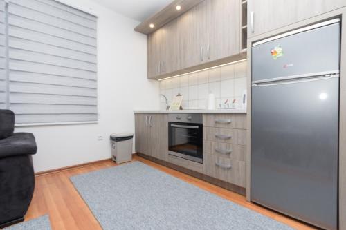 a kitchen with a stainless steel refrigerator and a couch at Apartman Emir 1 in Sarajevo