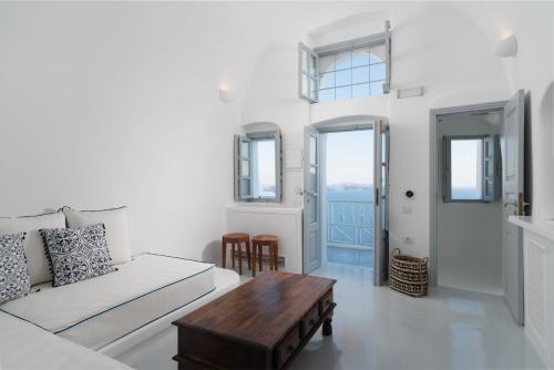 a room with a bed, table, chairs and a window at Oia Spirit Boutique Residences in Oia