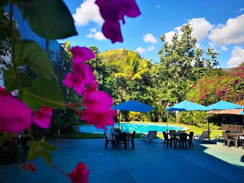 a pool with tables and chairs and blue umbrellas at Chanchamayo Inn Hotel in La Merced