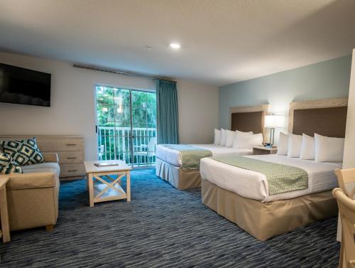 a hotel room with two beds and a balcony at Palmera Inn and Suites in Hilton Head Island