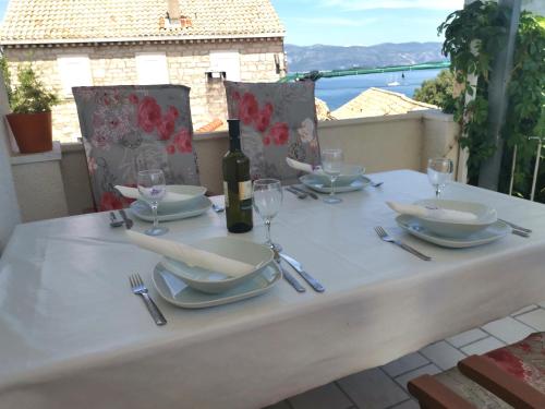 una mesa blanca con una botella de vino y copas en Apartments Ante, en Lumbarda