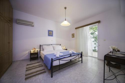 a bedroom with a bed with blue sheets and a window at Stegnailion in Archangelos