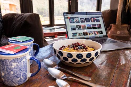 a bowl of cereal and a laptop on a table at Wolf Totem Steam Punk Guesthouse in Pisac