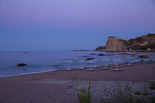 a beach with chairs and umbrellas and the ocean at Stegnailion in Archangelos