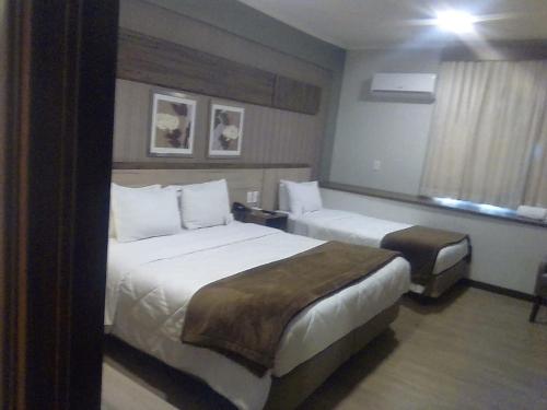a hotel room with two beds and a window at Klein Ville São Leopoldo in São Leopoldo