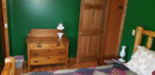 a bedroom with a bed and a dresser with a lamp on it at Cozy Country Farm Stay in Fredonia