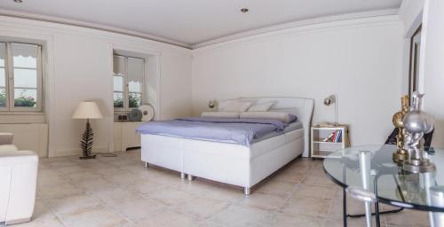 een witte slaapkamer met een bed en een glazen tafel bij President Boutique Apartment II in Brno