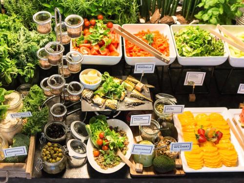 un buffet de légumes et autres denrées alimentaires sur une table dans l'établissement Q Hotel Kraków, à Cracovie