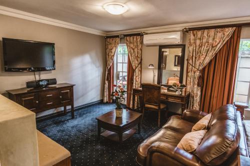 a living room with a couch and a desk and a television at Village Ridge Boutique Stays in Pretoria