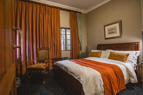 a hotel room with a bed and a chair and a window at Village Ridge Boutique Stays in Pretoria