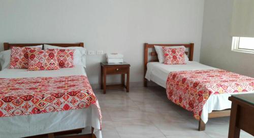 1 Schlafzimmer mit 2 Betten mit roten und weißen Decken in der Unterkunft Hotel Orquídea Neiva in Neiva