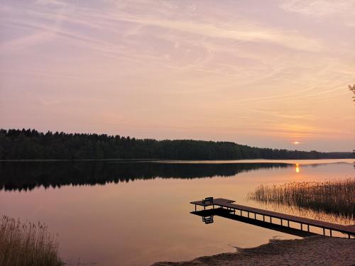 a dock on a lake at sunset at Apartamenty Mazurskie Klimaty (Cud Natury) in Tomaszkowo