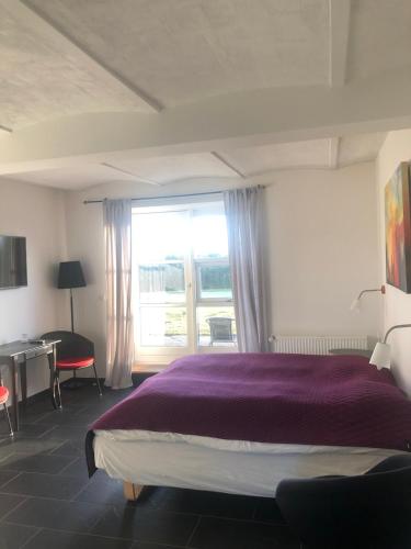 1 dormitorio con cama morada y ventana en Bjerrumgaard, en Ribe
