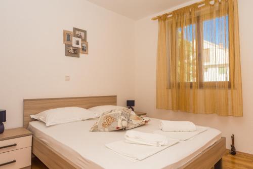 um quarto com uma cama com lençóis brancos e uma janela em Apartament Jukić em Sveti Filip i Jakov