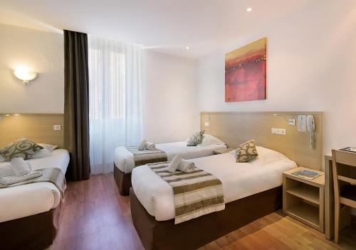 a hotel room with two beds and a television at Holzer II in Porto-Vecchio