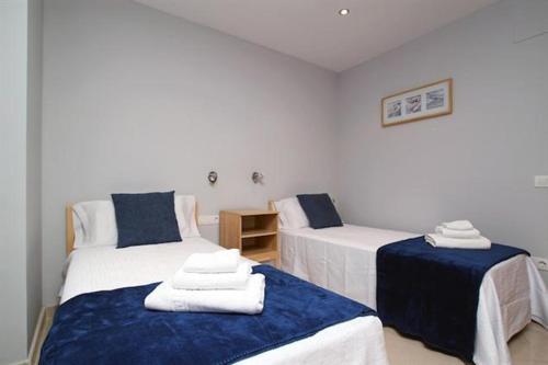 a room with two beds with blue and white sheets at Apartamentos Sitges in Sitges