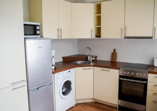 a kitchen with white cabinets and a washer and dryer at Stuudio 17 in Kuressaare