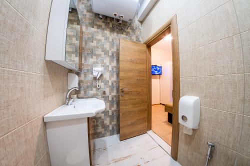 een badkamer met een wastafel, een spiegel en een deur bij Sofia Industrial Life Apartment in Sofia