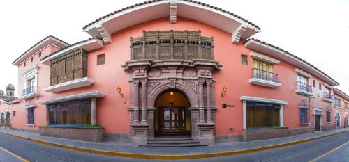 a pink building with an archway on a street at DM Hoteles Ayacucho in Ayacucho