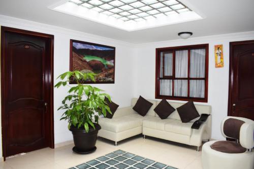 a living room with a white couch and a plant at Hotel Londres in Pasto